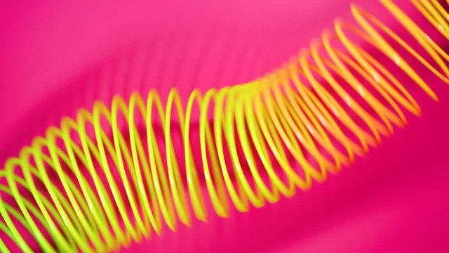 Vintage Retro Abstract Background. Rainbow Coloured Spring Moves Across a Pink Background In a Wave Like Pattern. Rainbow Spiral Spring Motion Wave a Bright Beautiful Background.