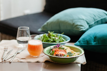 Healthy and light lunch  - fresh green salad, delicious bowl with smoked salmon, beans, cauliflower and freshly squeezed orange juice with pulp. Raw seasonal ingredients. Close up, front view