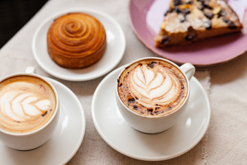 Cozy and romantic. Winter hot cappuccino drink in white cups. Delicious french pastry for breakfast.