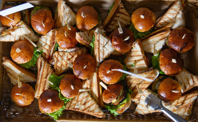 Hamburgers and sandwiches in a large basket, top view.