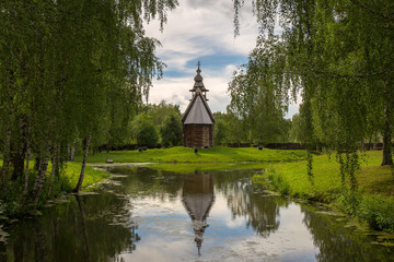 The old wooden Church is surrounded by birches on the shore of the pond. Kostroma, Russia.