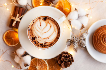 Cozy and romantic holiday time. Winter hot drink in white cup. Christmas lights on, festive mood, atmosphere of relax, family time. Flat lay, top view, white background.