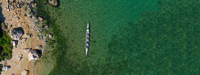 Aerial drone top panoramic view of sport canoe rowing synchronous athletes competing in tropical...