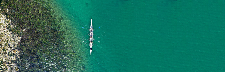 Aerial drone top panoramic view of sport canoe rowing synchronous athletes competing in tropical exotic lake