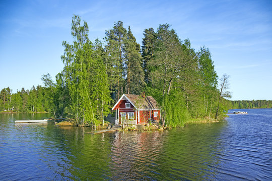 Island on lake in Finland with red summer cottage