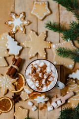 Winter hot drink: white mug with hot chocolate with marshmallow and cinnamon. Cozy home atmosphere, festive holiday mood. Rustic style, wooden background. Homemade gingerbread cookies. Flat lay