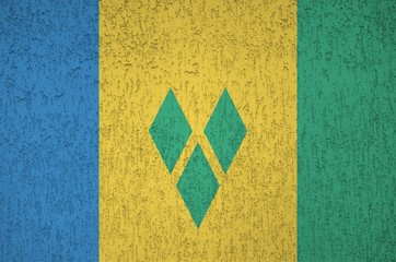 Saint Vincent and the Grenadines flag depicted in bright paint colors on old relief plastering...