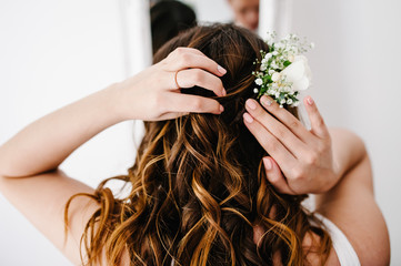 Fototapeta premium The bride corrects wreath of flowers at his head. A look on the back of the woman's hands and hair. Wedding Morning.