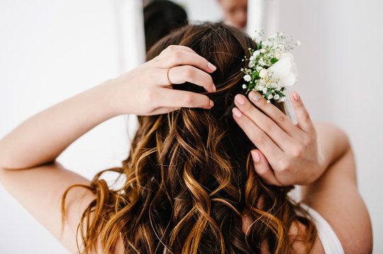 The bride corrects wreath of flowers at his head. A look on the back of the woman's hands and hair. Wedding Morning.