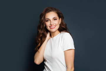 Obraz premium Happy beautiful model woman wearing white t-shirt on gray background