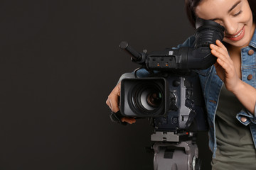 Operator with professional video camera on black background, space for text