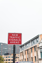 Red street sign with white letters  saying ,,new trafic signaks ahead,,