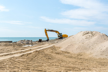 Excavator doing an earthwork on a shore to protect from erosion.