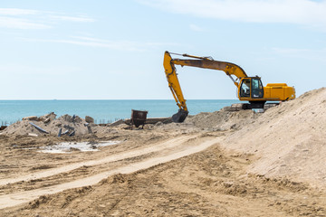 Excavator doing an earthwork on a shore to protect from erosion.