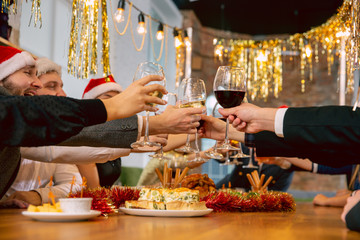 Happy co-workers celebrating while company New Year and Christmas party. Young caucasian people in celebrate attire talk, drink wine, cheers. Concept of office culture, teamwork, friendship, winter.