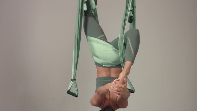 Yoga master in aerial yoga hammock desaturated calm colors minimalist studio footage about aerial yoga