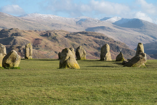 Cumbria, England, UK: part of the Castlerigg neolithic stone circle on a fresh bright day with snow on the peaks behind.   Erected around 3000BC.