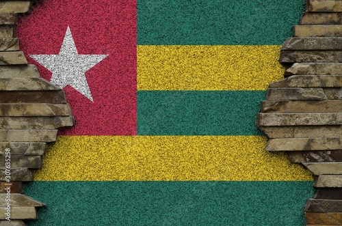 Togo flag depicted in paint colors on old stone wall closeup. Textured banner on rock wall background