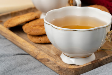 White porcelain cup of tea and oat cookies on a table