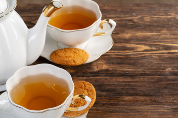 White porcelain cup of tea and oat cookies on a table