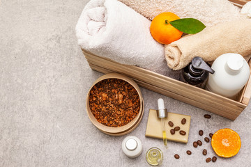 Coffee and tangerine spa concept. Towels, oil, scrub, soap, lotion. Natural ingredient, wooden box. Stone concrete background