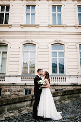 Fototapeta premium Newlyweds are standing and hugging, kissing near ancient restored architecture, old building, old house outside, vintage palace outdoor.