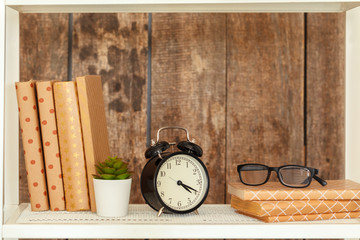 Stylish white bookshelf against grunge wooden wall