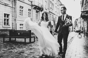 A loving wedding couple are walking along the streets of the city of Lviv. Black and white photo.