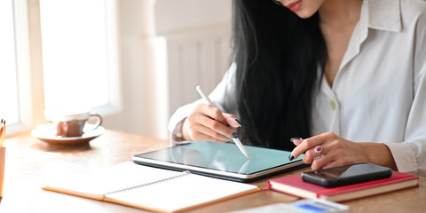 Closeup young female working with tablet computer and stylus pen.