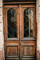 Old brown wooden door of the house with windows, building. Ancient vintage closed door from the street.