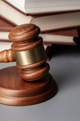 Brown wooden gavel with stack of books on gray table