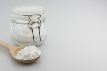 Close-up of tapioca starch or flour powder in wooden spoon on white background