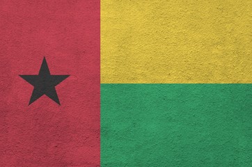 Guinea Bissau flag depicted in bright paint colors on old relief plastering wall. Textured banner...