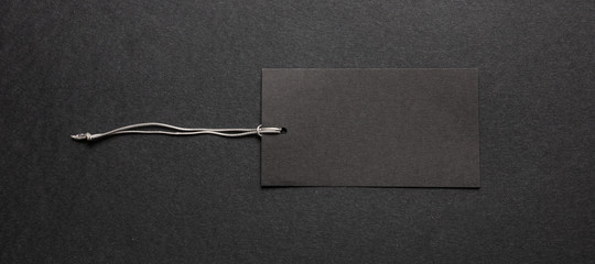 Black recycled price card with silver elastic band against black background