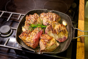 Close-up view of a raw veal steak with spices being prepared in a grill pan
