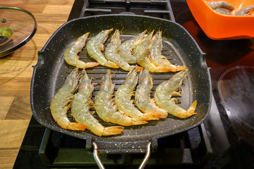 Prawns shrimps roasted on frying grill pan close-up in selective focus. Grilled seafood.