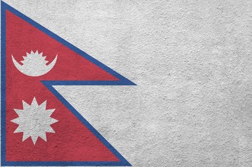 Nepal flag depicted in bright paint colors on old relief plastering wall. Textured banner on rough...