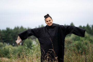 Emotional woman charming actress with dark hair in black loose dress with long sleeve holds mask in...