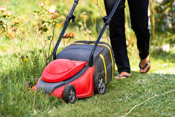 Closeup of a man with a lawn mower cutting the grass. Selective focus. Red special manual technic.