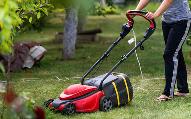 Gardener mowing the lawn at backyard. Landscape, terrain at backyard. Special equipment for landscape, terrain. Gardening concept. Closeup.