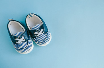 Baby boy shoes, childhood concept on pastel blue background, top view.