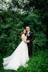 Romantic wedding moment, couple of newlyweds, portrait looking at the camera in nature in the park. Wedding ceremony.