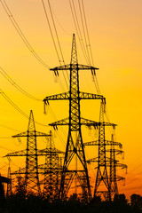 Energy Distribution Network - Electricity Pylons against Orange and Yellow Sunset. Selective focus.