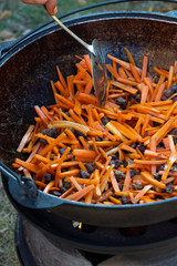 Fry sliced carrots in pilaf oil. Onions and carrots are fried in a pan in sunflower oil