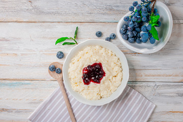Milchreis mit Früchten im Teller auf hellem Holz