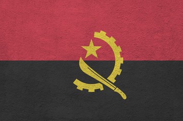 Angola flag depicted in bright paint colors on old relief plastering wall. Textured banner on rough...
