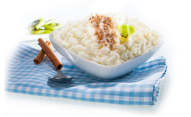 Milchreis mit Zimt und Kiwi im Teller auf weißem Untergrund