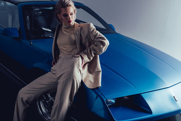 attractive and stylish woman in suit sitting on retro car