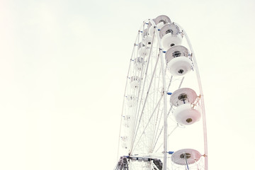 A beautiful retro vintage ferris wheel in a clear white pale sky background perfect for copy and text. Engineering wheel made for funfair entertainment and amusement rides.
