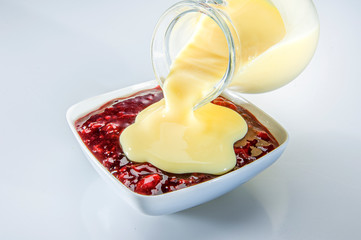 Schale rote Grütze mit Früchten mit Karaffe Vanillesoße